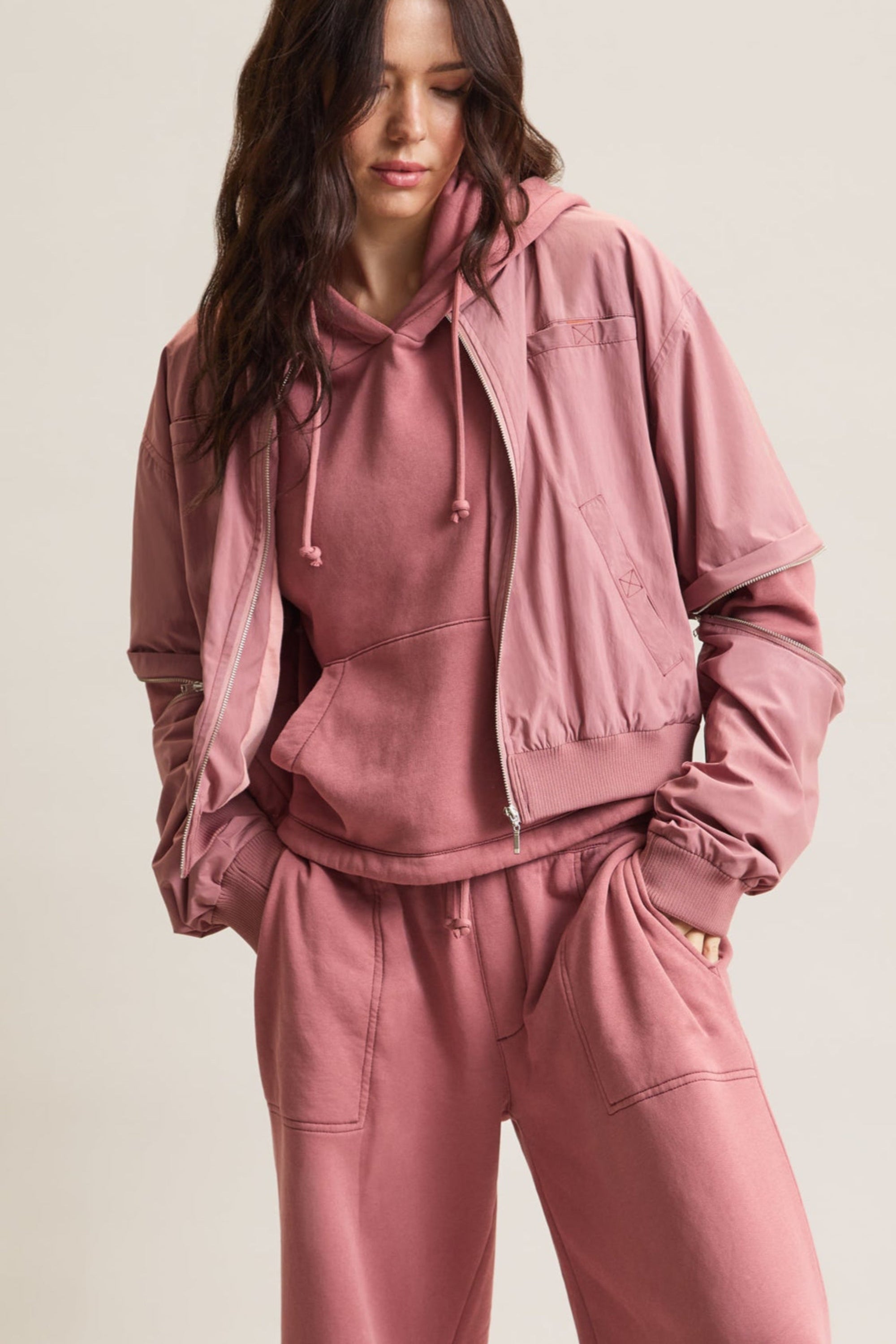 Women's HRMN8 dusky dusty pink convertible nylon jacket with removable sleeves, ribbed cuffs, and a relaxed fit. Designed for athleisure, casual wear, and transitional styling over your favourite activewear set. Lined with soft cotton jersey for comfort and features four pockets, including two at the chest for added functionality. A modern, lightweight layering piece for all seasons.