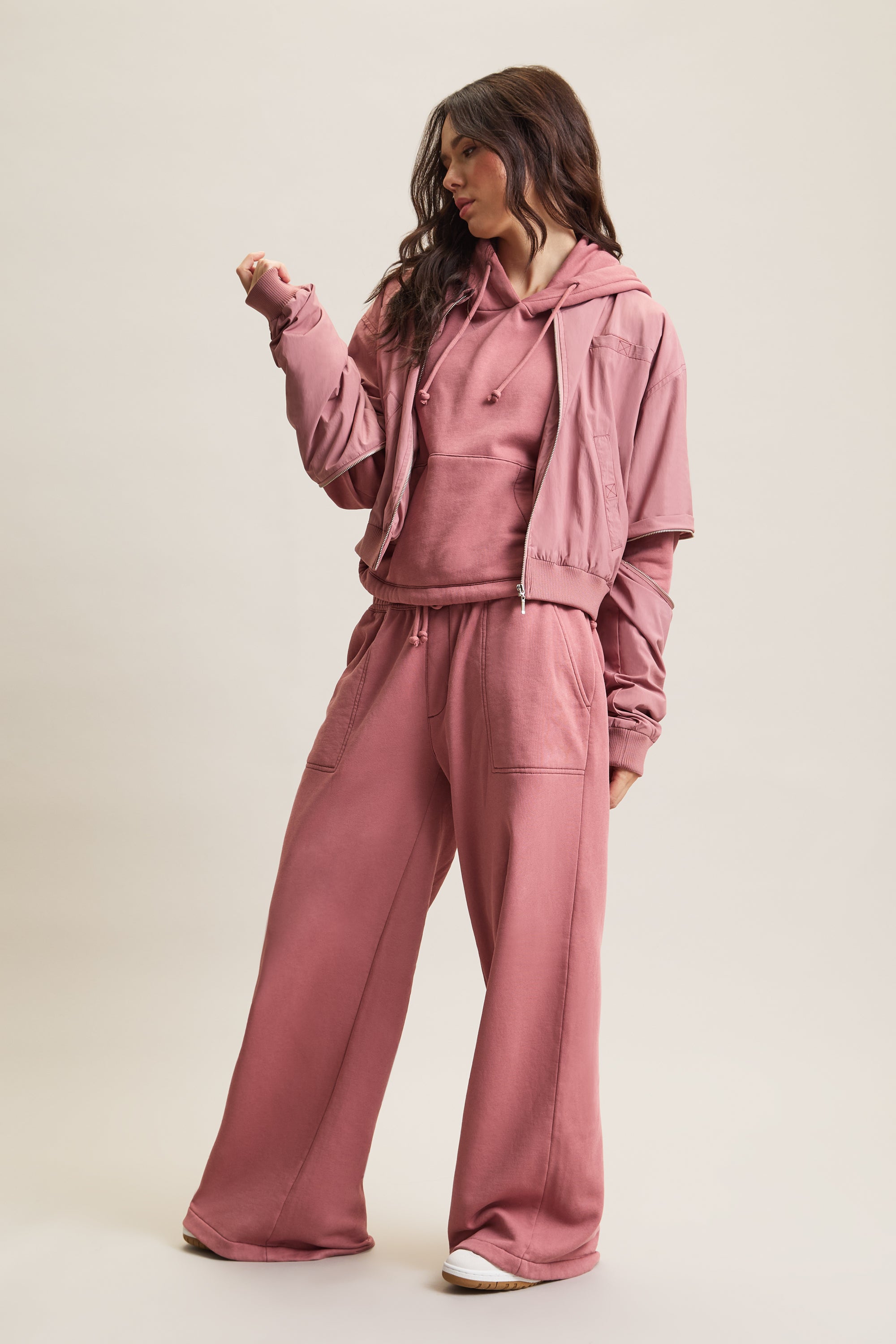 Women's HRMN8 dusky dusty pink convertible nylon jacket with removable sleeves, ribbed cuffs, and a relaxed fit. Designed for athleisure, casual wear, and transitional styling over your favourite activewear set. Lined with soft cotton jersey for comfort and features four pockets, including two at the chest for added functionality. A modern, lightweight layering piece for all seasons.