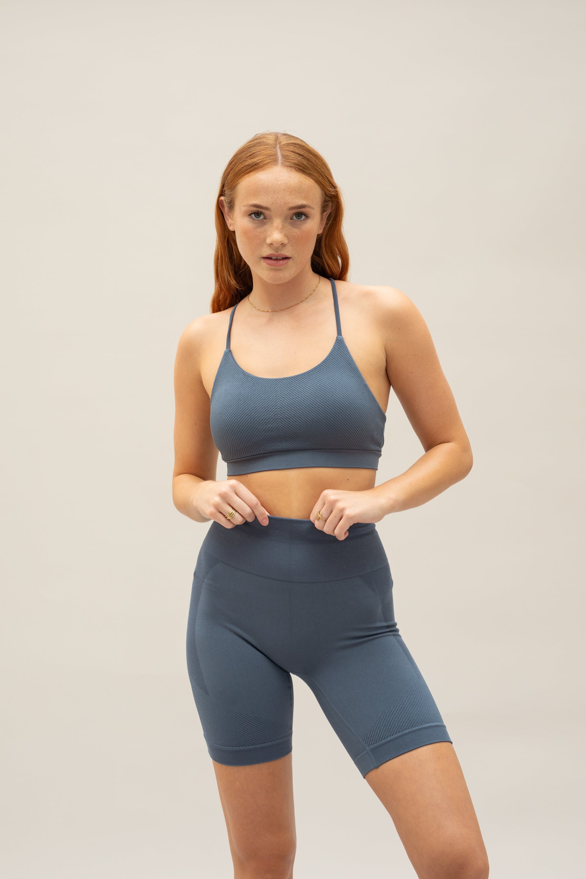 Model wearing steal blue shorts and steal blue supportive sports bra for sustainable activewear brand, Jilla.