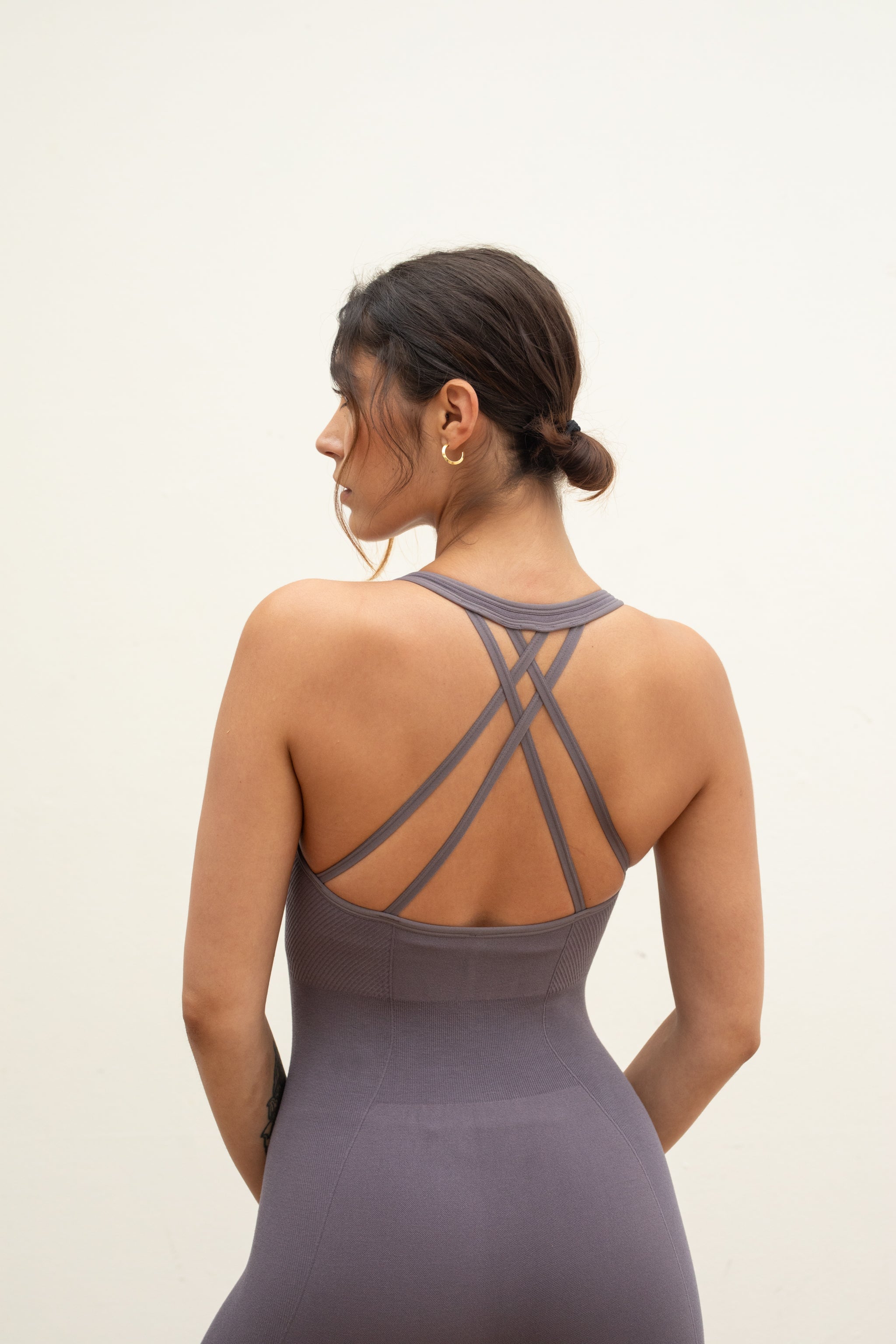 Model wearing grey one piece for sustainable activewear brand, JillaTwilight ash light brown purple seamless sculpting shaping one piece bodysuit with built in shelf bra and removable pads for yoga, pilates, gym and exercise by sustainable activewear brand Jilla Active