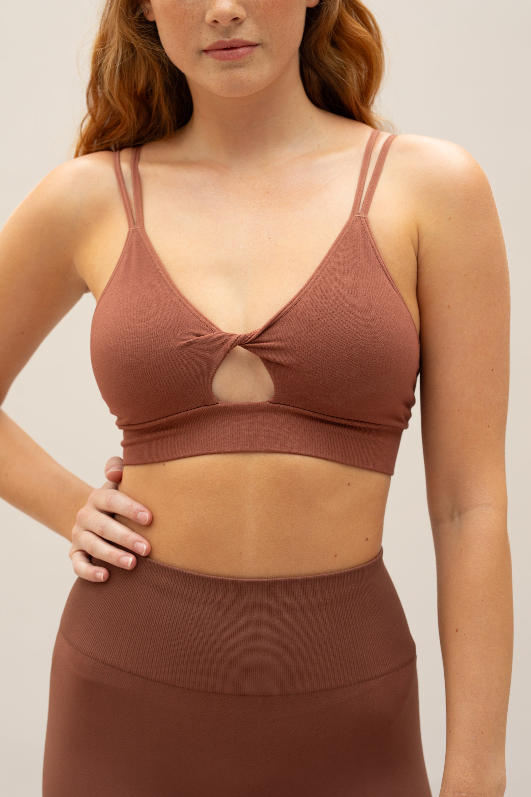 Brown supportive twisted from sports bra and brown high waisted flare leggings from sustainable activewear brand, Jilla. 