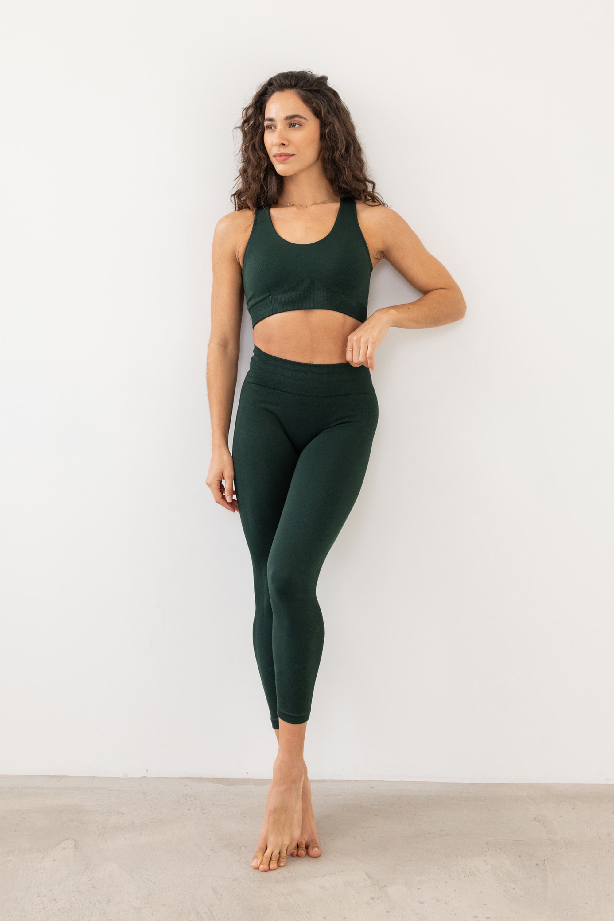 Dark green sculpting, supporting, contouring and shaping V neck sports bra with underband and black detail from recycled seamless fabric for yoga, pilates, gym, barre, running, gym and exercise.