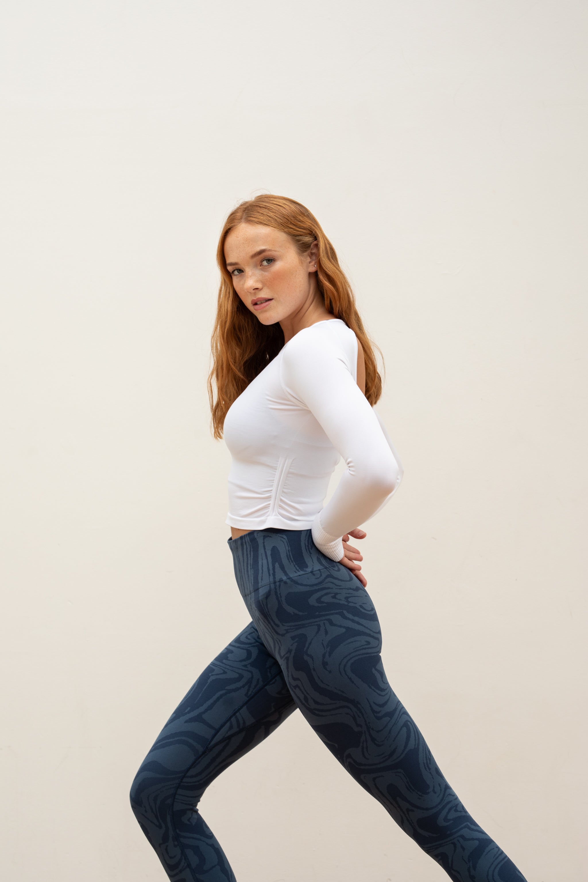 White long sleeve recycled crop top with blue leggings from sustainable women's activewear brand, Jilla. 
