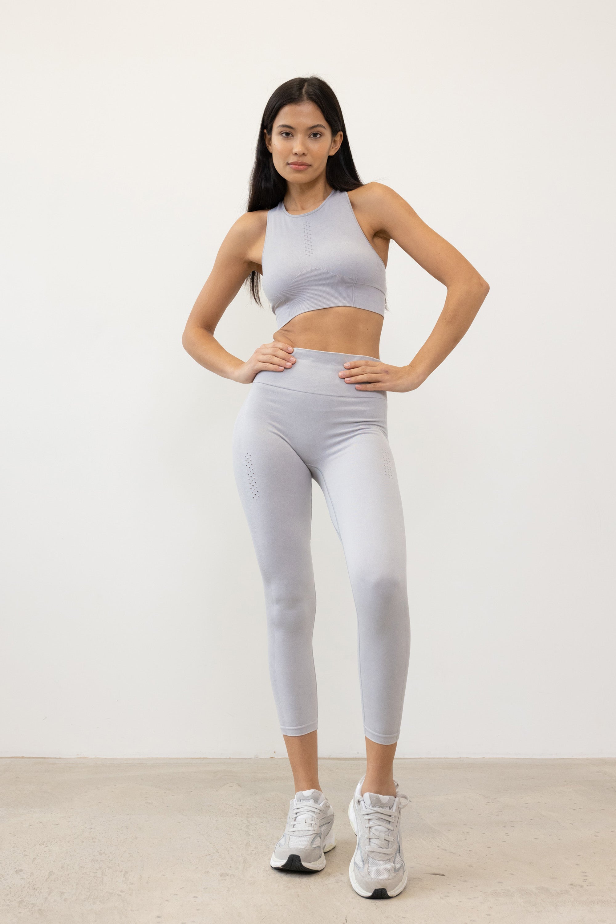 Our light grey Aquarius Recycled Leggings - crafted for seamless performance in your yoga flows, barre workouts, and reformer classes. Made from four-way stretch fabric, they move effortlessly with you. Designed with flattering ribbing and an acid wash effect, each pair is unique. The high-rise ribbed waistband with internal elastic ensures they stay in place during your entire class, while the double-layered gusset provides all-day comfort and flexibility. 