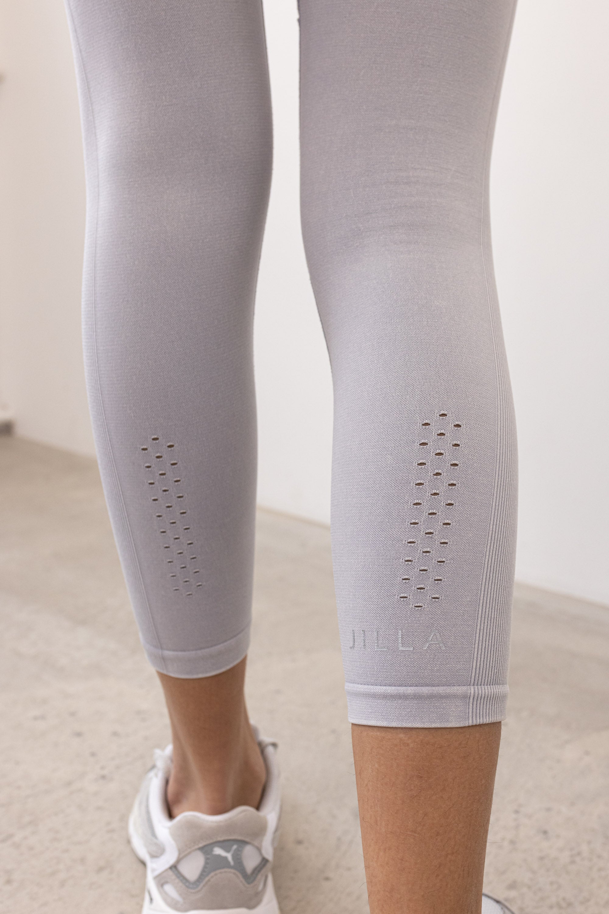 Our light grey Aquarius Recycled Leggings - crafted for seamless performance in your yoga flows, barre workouts, and reformer classes. Made from four-way stretch fabric, they move effortlessly with you. Designed with flattering ribbing and an acid wash effect, each pair is unique. The high-rise ribbed waistband with internal elastic ensures they stay in place during your entire class, while the double-layered gusset provides all-day comfort and flexibility. 