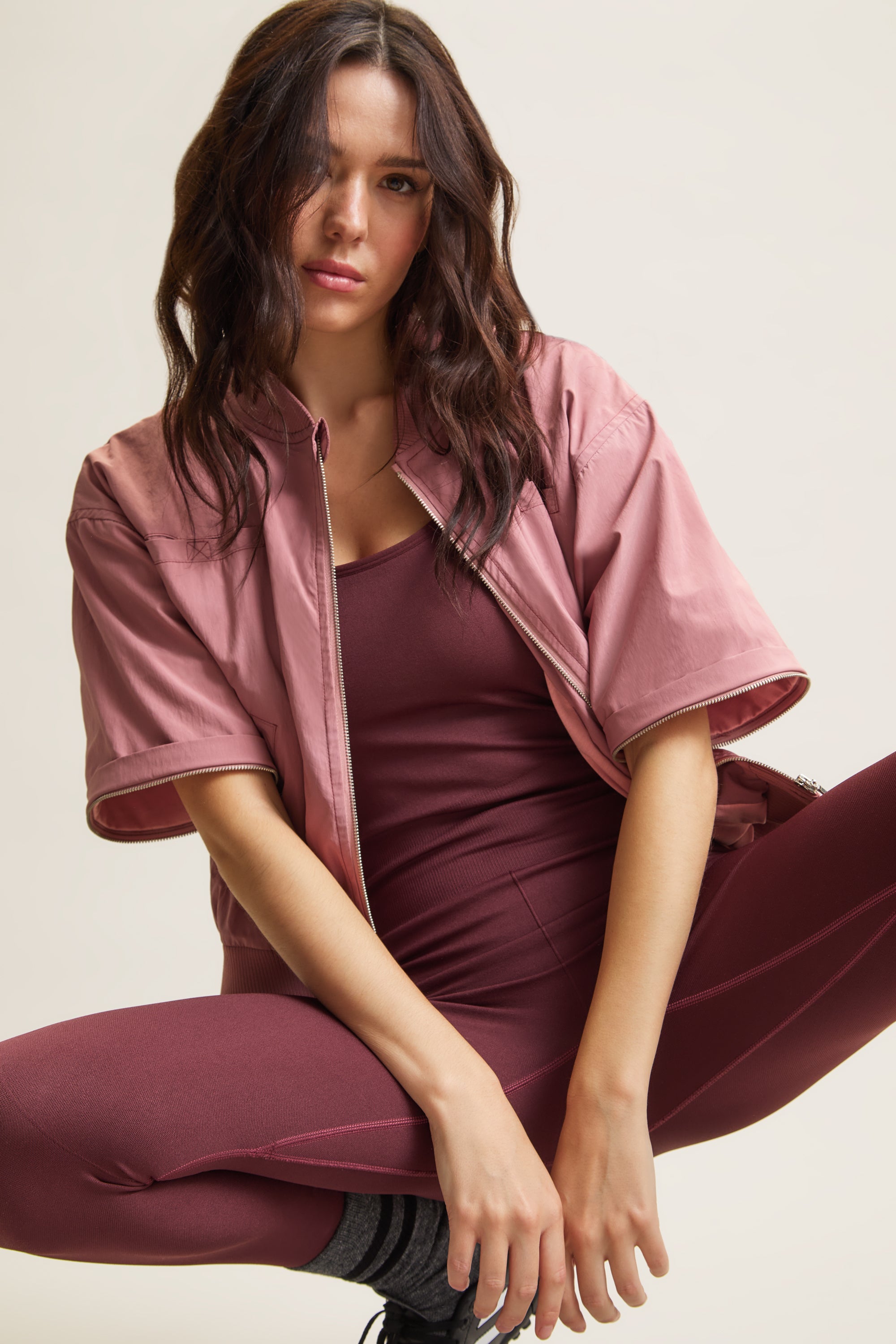 Women's HRMN8 dusky dusty pink convertible nylon jacket with removable sleeves, ribbed cuffs, and a relaxed fit. Designed for athleisure, casual wear, and transitional styling over your favourite activewear set. Lined with soft cotton jersey for comfort and features four pockets, including two at the chest for added functionality. A modern, lightweight layering piece for all seasons.