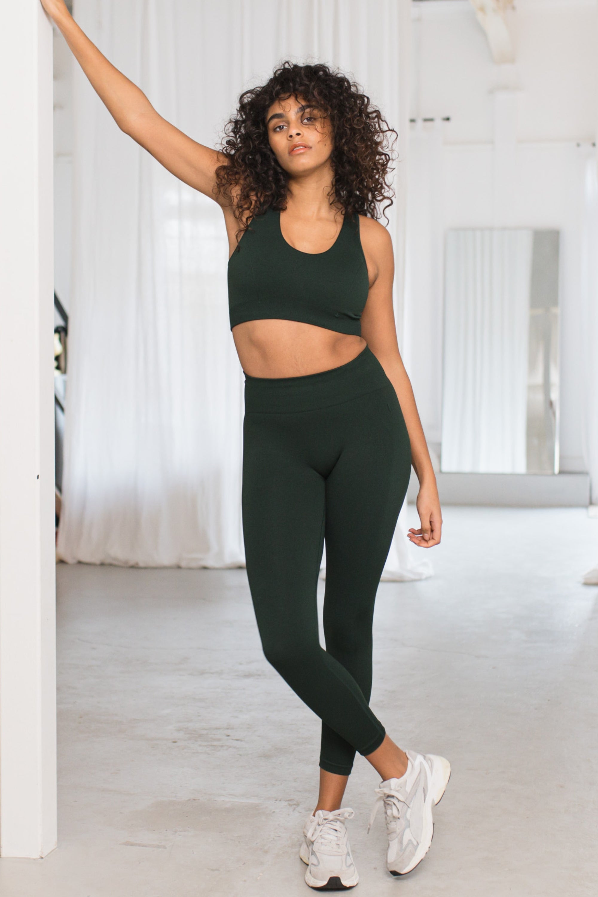 Dark green sculpting, supporting, contouring and shaping V neck sports bra with underband and black detail from recycled seamless fabric for yoga, pilates, gym, barre, running, gym and exercise.