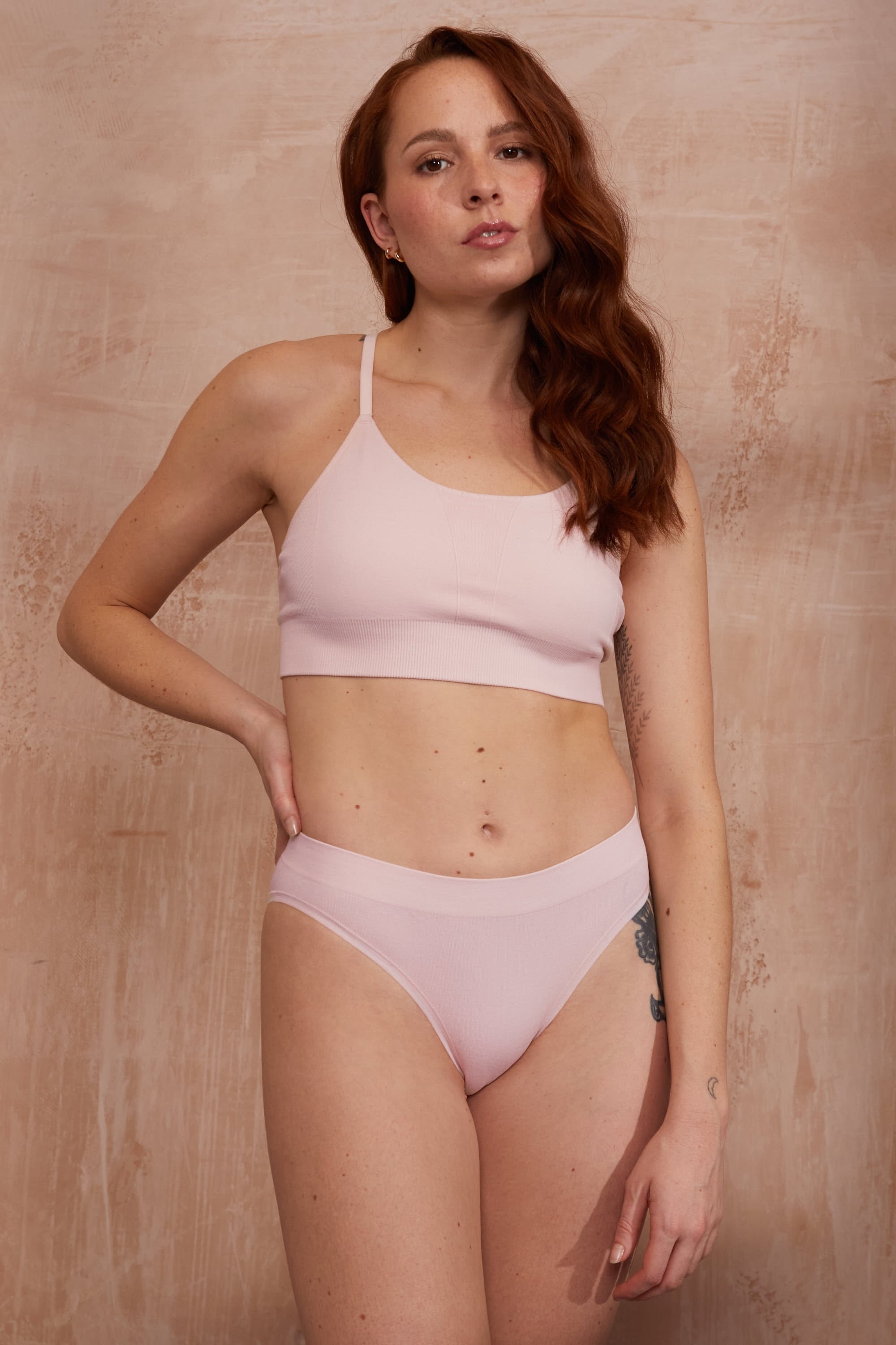 Model wearing pink top and pink thong.